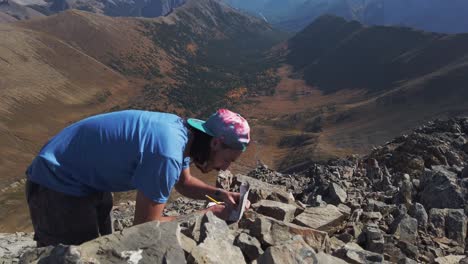 excursionista escribiendo un mensaje de nota en el pico de la montaña sobre el valle cerca de un círculo kananaskis alberta canada