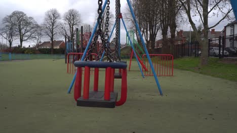 los niños se balancean en un patio de recreo público vacío durante la pandemia de coronavirus