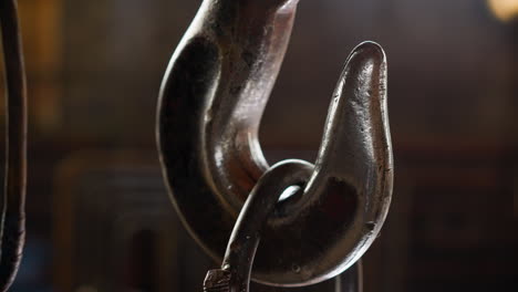 old metal hook with hanging load in factory warehouse