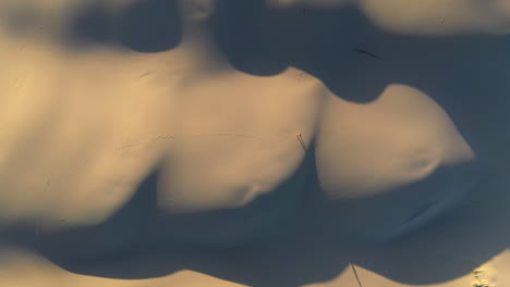 cinematic rising drone shot of man walking on sand dunes