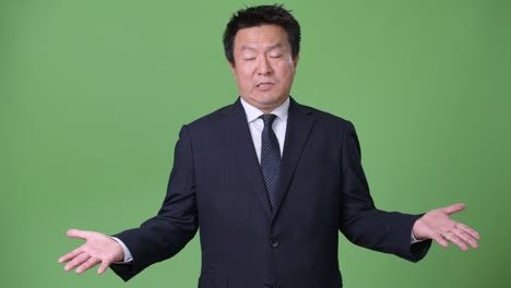 mature japanese businessman against green background