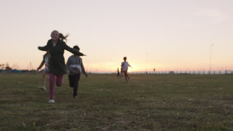 group of happy children portrait running playing cheerful in grass field at sunset enjoying fun games together