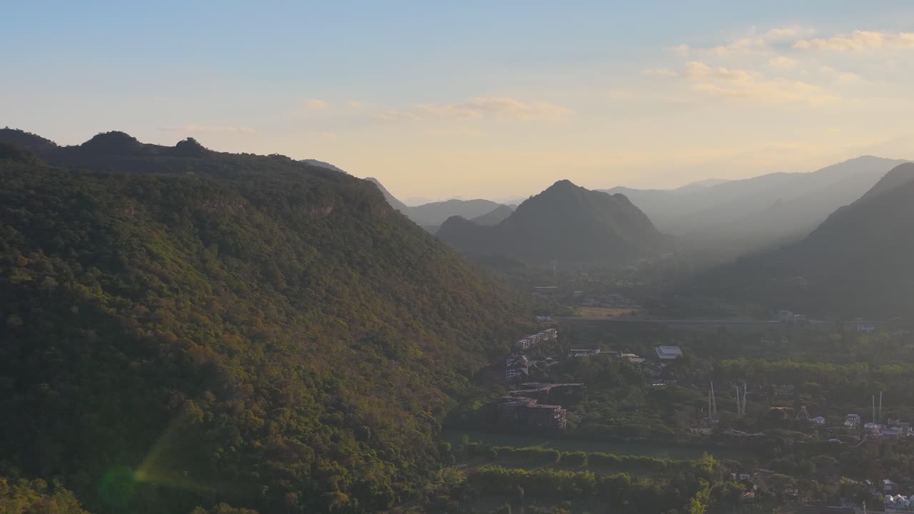 Uma tomada aérea ampla de drone captura a luz da hora dourada sobre uma exuberante paisagem de vale montanhoso tropical