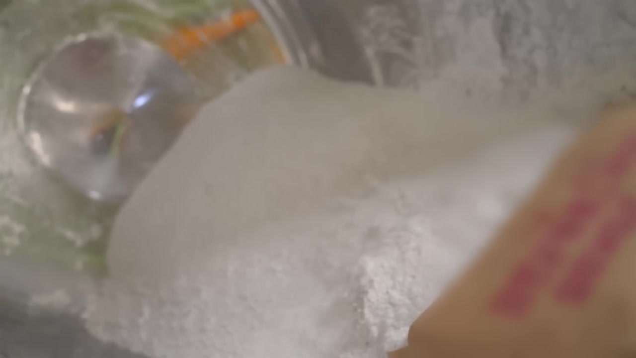 Operaio che svuota un grande sacco di carta di polvere bianca in un tamburo miscelatore industriale in una fabbrica di gesso