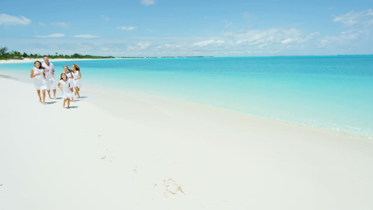 Happy Caucasian family walking on a tropical beach