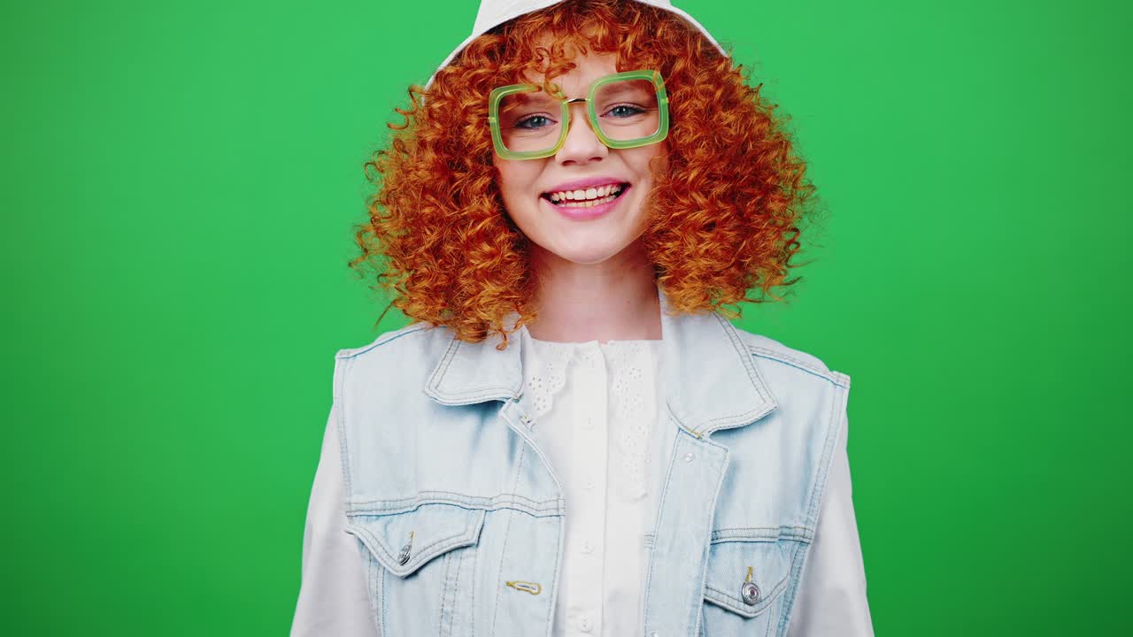 bonita mujer pelirroja rizada con sombrero de panama y gafas mostrando el gesto del corazón y enviando un beso de golpe, guiñando el ojo a la cámara
