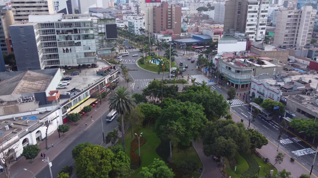 Drone flies over public called "Parque Kennedy" filled with green trees. Located in Miraflores district of Lima, Peru.