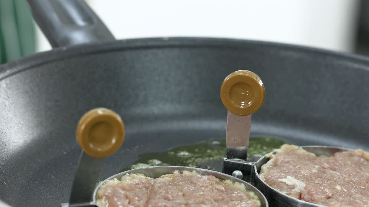 自家製ハンバーガーの材料準備。熱いガスコンロで溶かしバターを使い、型に入れた生豚肉を調理し、美味しく香ばしい香りを出す手。