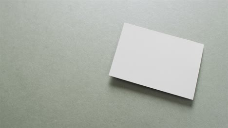 Close-up-of-stack-of-white-business-cards-on-grey-background,-copy-space,-slow-motion