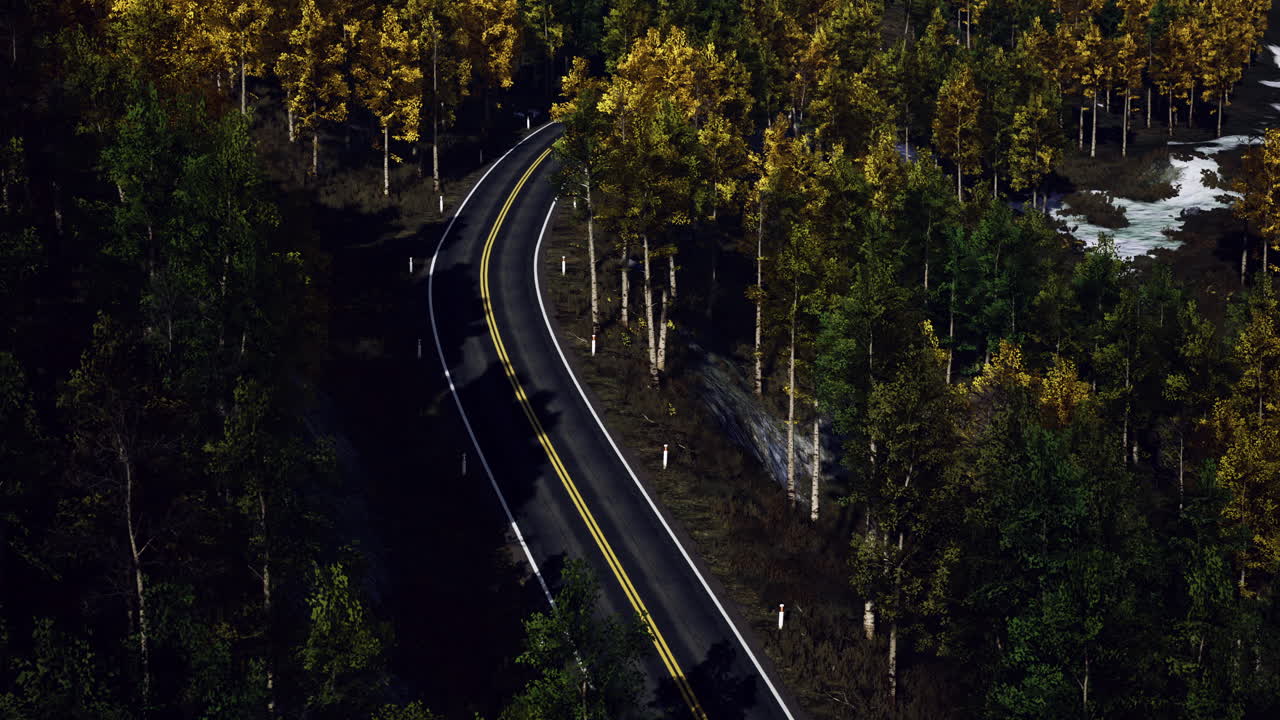 Winding road through vibrant autumn trees surrounded by tranquil scenery