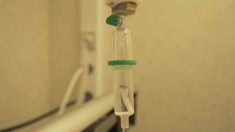 close view of medical plastic giving set transparent reservoir filled it intravenous fluid and slow drops for treatment of patient in hospital during coronavirus pandemia