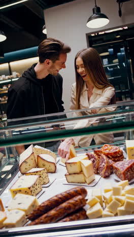 couple shopping for cheese and meats at a grocery store