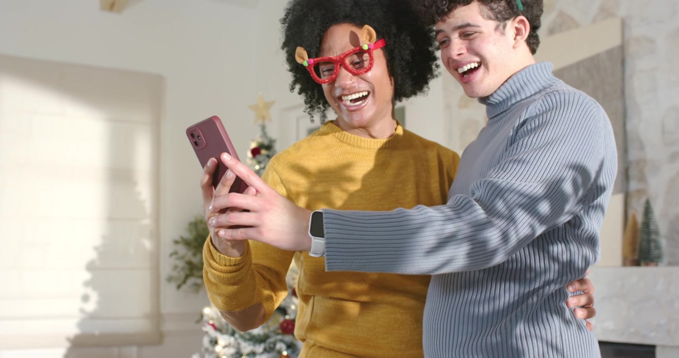 Two men holding smartphone reacting to message and showing antlers while checking watch at home