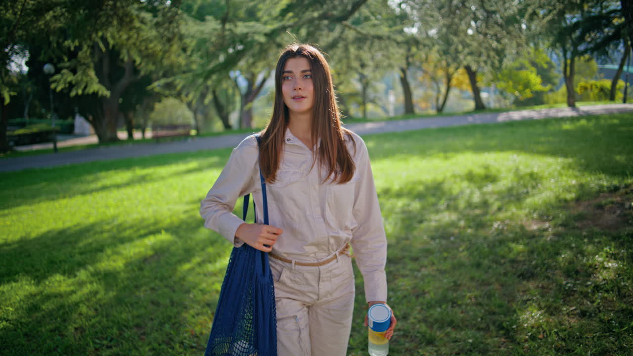 빛 공원에서 산책하는 편안한 소녀. 산책하는 평온한 자연을 즐기는 행복한 여성