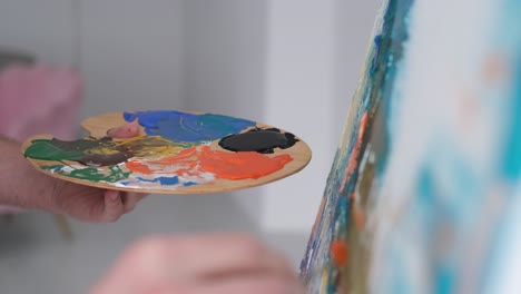 close-up of artist's hand holding a paint palette