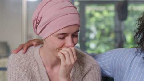 upset young woman patient wearing headscarf receiving chemotherapy treatment for breast cancer being comforted by female patient 2