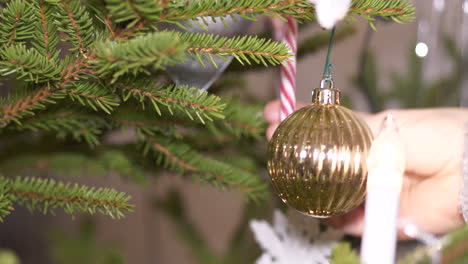 Close-up-of-hand-putting-Christmas-cane-and-finishing-touches-on-Christmas-tree