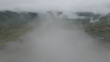 drone se mueve a través de las nubes para revelar una vasta área de arrozales