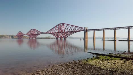 forth railway bridge with a train passing over it on its way to edinburgh on a hot calm day