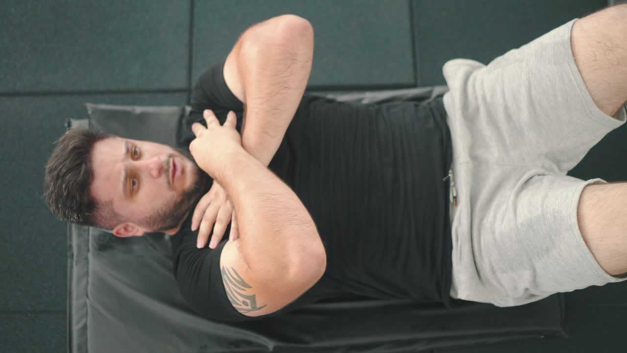 toma de arriba hacia abajo de un joven fuerte haciendo abdominales en el gimnasio