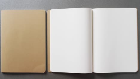 Close-up-of-open-blank-and-book-brown-notebook-with-copy-space-on-gray-background-in-slow-motion