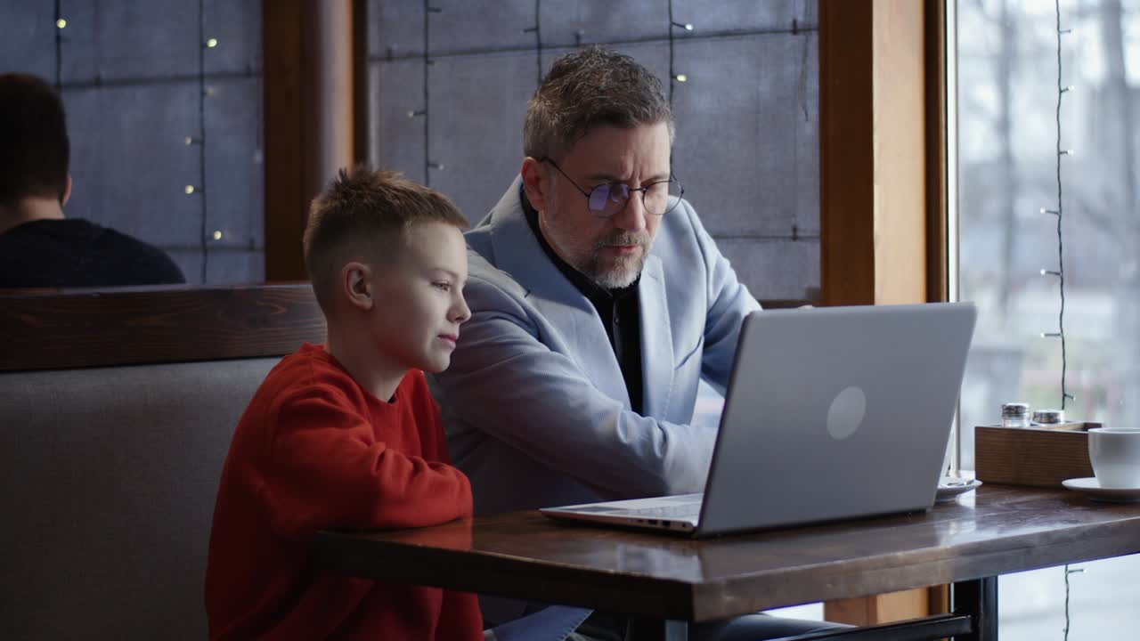 Ayah dan anak laki-laki menggunakan laptop bersama-sama