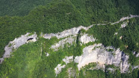 Majestuosas-Imágenes-Aéreas-Sobre-La-Carretera-Con-El-Tráfico-Que-Pasa-A-Través-De-Un-Bosque-Impresionante,-Una-Gran-Altitud-Y-Una-Vista-Sinuosa-De-La-Carretera,-Capturadas-En-La-Provincia-De-Hebei,-China