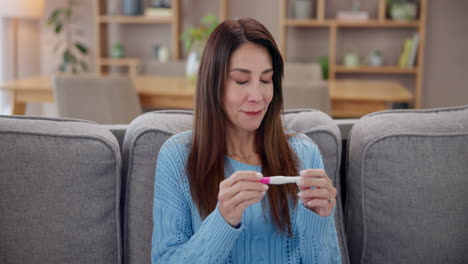 mujer mira con emoción una prueba de embarazo positiva