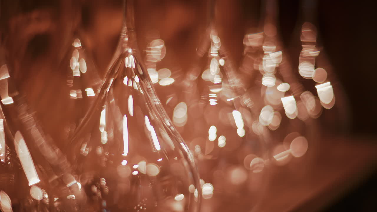 Close up view of multiple glass vessels softly illuminated with warm light that creates a golden bokeh effect in the background