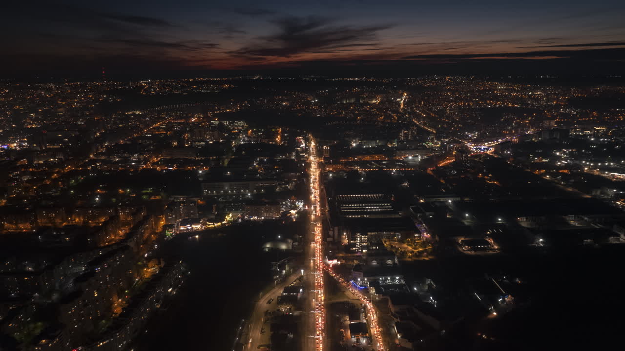 Aerial drone timelapse view of Chisinau at sunset, Moldova. View of the city with multiple buildings, lake, roads with traffic, illumination