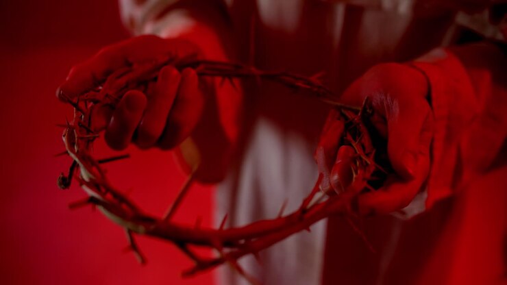 Hands holding crown of thorns in glowing red light for Christianity, Easter, church, worship, Sunday visual. Representation of the cross, Jesus, salvation, temptation, etc.