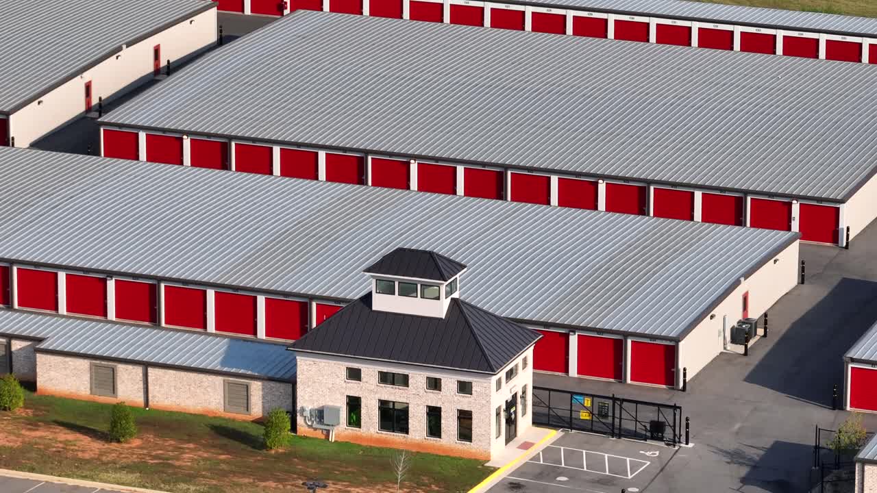 Red colored garages of warehouse temporary storages in American town. Aerial wide shot. Several self unit storage buildings at daytime