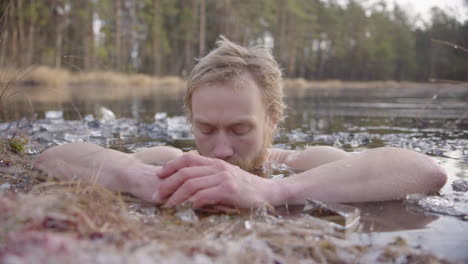 an ice bather focuses on conscious breathing as he sits in a frozen lake