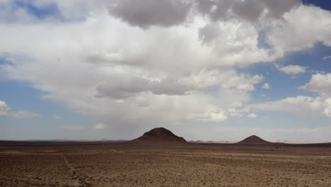 Un-Vasto-Y-Desolado-Paisaje-Desértico-Con-Dos-Montañas-Volcánicas-Extintas-En-Forma-De-Cono---Vista-Aérea-De-Paralaje