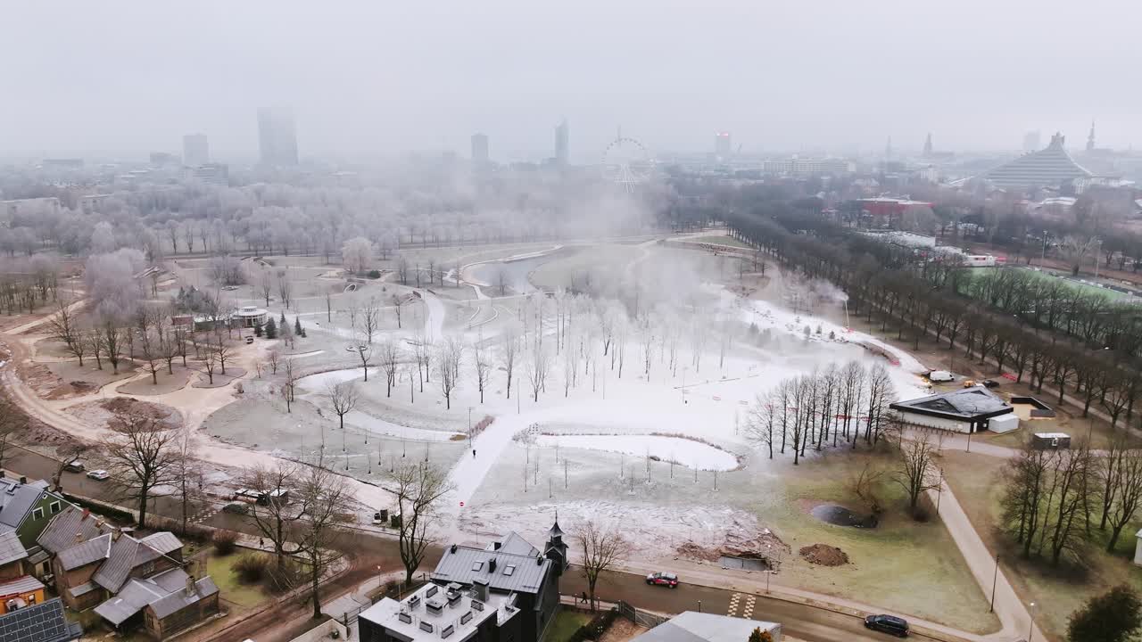 Urban park in Latvia blanketed with fog and fake snow on cold February day