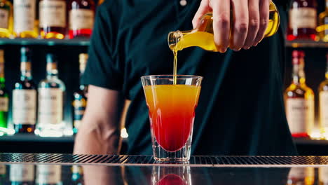 bartender pouring a colorful layered cocktail at a bar