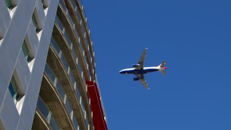 airplane flying over modern highrise building