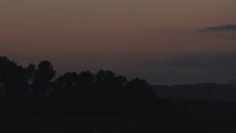 4k timelapse of beautiful sunset behind a forest and some nice clouds. the sun hides behind the mountain