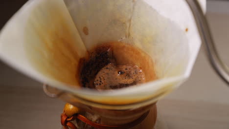 Watering-the-coffee-pot-with-a-view-of-a-white-filter-placed-in-a-glass-jar-for-dripping-coffee-pouring-water-on-a-coffee-and-around-the-filter-trapped-in-slow-motion-at-120-FPS