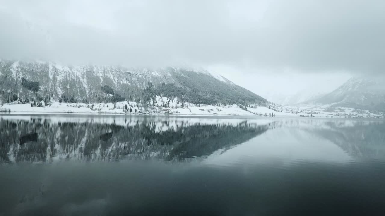 아름다운 눈으로 인 나무와 산을 배경으로 평화로운 얼어붙은 호수의 공중 포워드