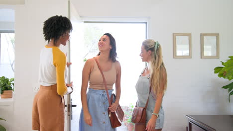 diverse female friends laughing and pointing while enjoying time together indoors