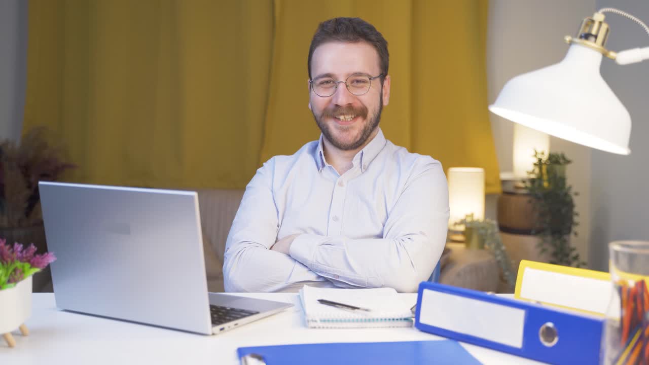 Uomo che lavora da casa che sorride alla telecamera