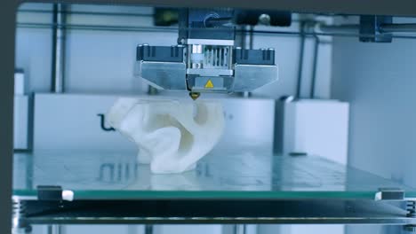 la moderna impresora 3d imprime figuras de primer plano macro. la impresora tridimensional automática 3d realiza el modelado de colores blancos de plástico en el laboratorio. el procesamiento de impresión 3d con fondo blanco