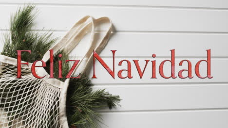 feliz navidad text in red over christmas branches on white wood background
