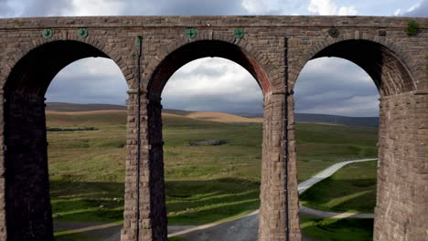 toma aérea volando hacia atrás a través del viaducto ribblehead que revela la estructura de piedra y los pozos de arcilla