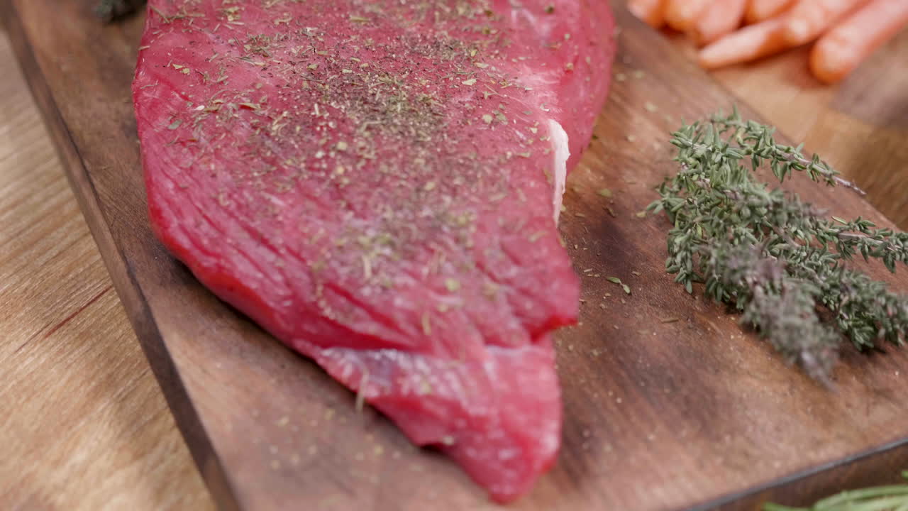 Raw Beef with Thyme and Carrots on a Wooden Board