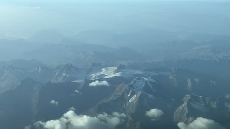 Aerial-view-of-the-Alps-with-almost-no-snow-due-to-climate-change,-shot-from-a-jet-cabin-flying-at-10000m-high