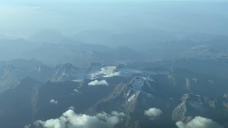 aerial view of the alps with almost no snow due to climate change, shot from a jet cabin flying at 10000m high