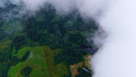 aerial above clouds over rural countryside farmland landscape drone forest nature
