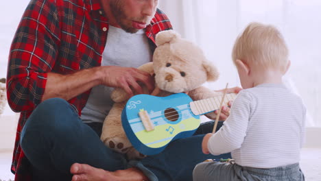 dad and toddler playing with instruments and teddy, close up